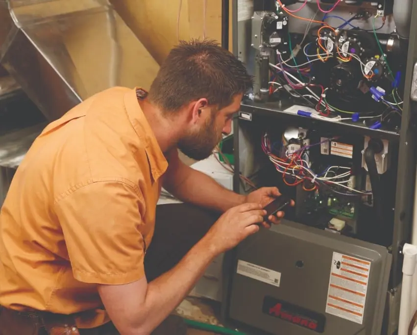 Berner A/C & Heat technician servicing an Amana gas furnace during maintenance visit