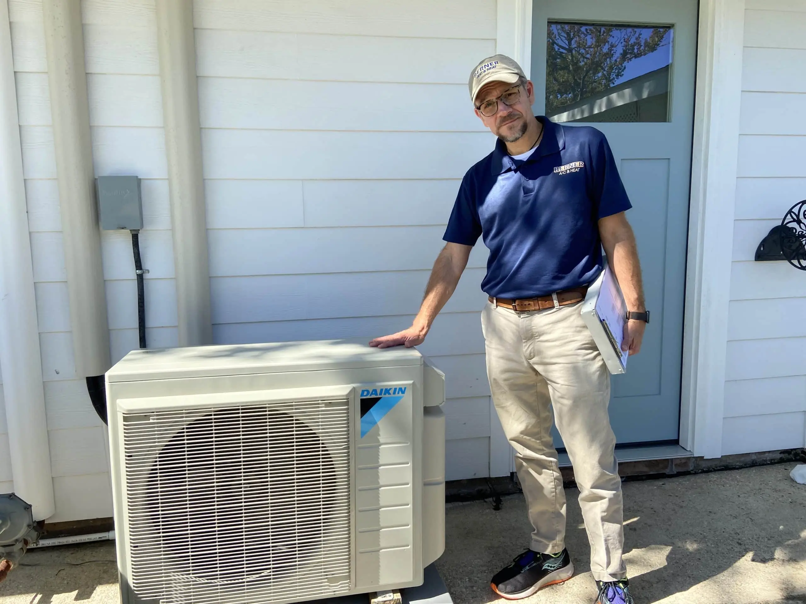 Supervisor inspecting ductless mini-split outdoor unit during installation
