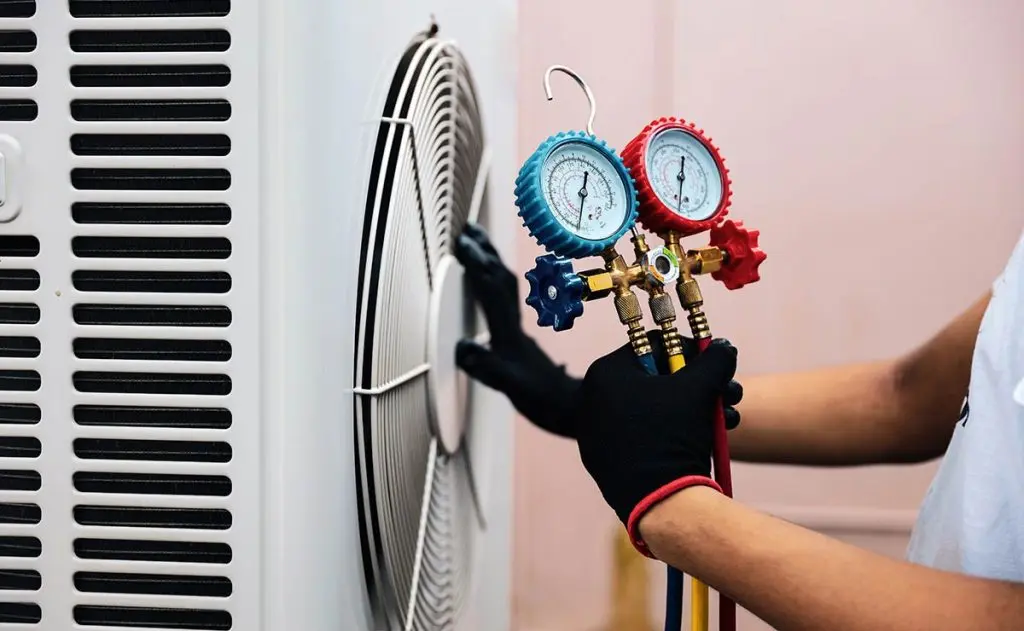 HVAC technician checking and diagnosing air conditioning system during maintenance visit