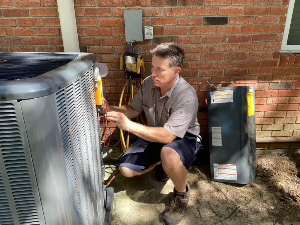 Berner A/C & Heat service technician inspecting outdoor AC condenser unit