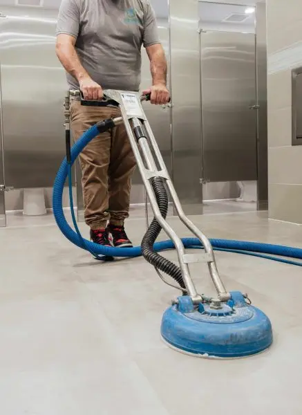 A janitor providing commercial floor cleaning services to a Boca Raton office bathroom