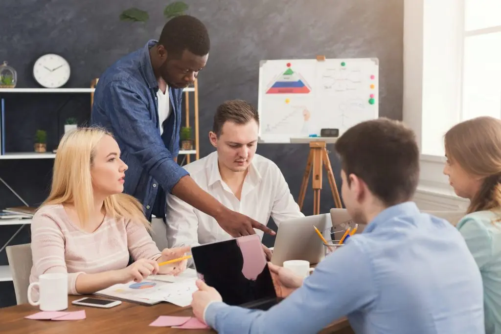 company coworkers discussing ideas in office e1612887135828