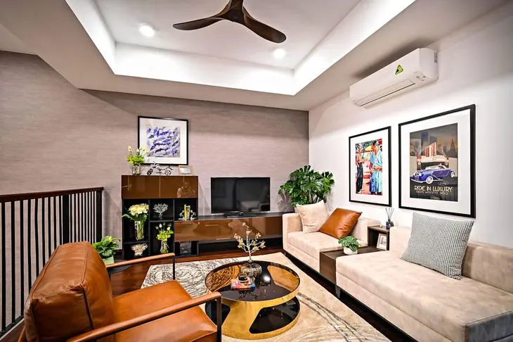 Modern living room with a beige sofa, brown armchair, wall art, TV, plants, and a glass coffee table beneath a ceiling fan.