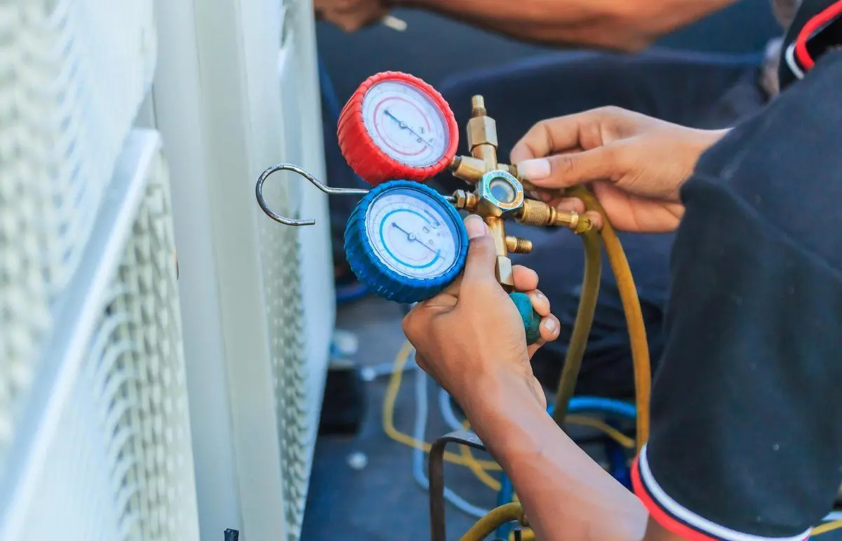 Technician adjusting HVAC gauges on an air conditioning unit.