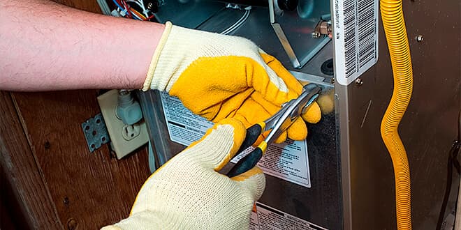 Gloved hands working on a furnace unit