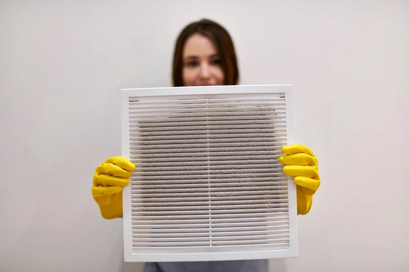 Person in yellow gloves holding a dirty air filter.