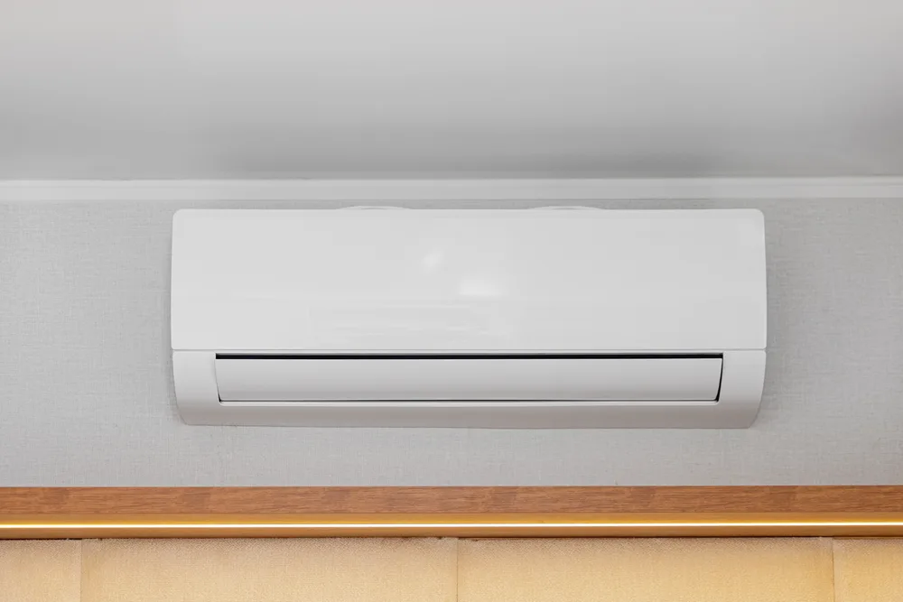 Wall-mounted white air conditioning unit against a light gray wall.