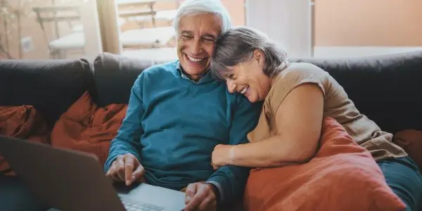 Retired couple watching funny video content on a laptop screen Retired couple watching funny video content on a laptop screen