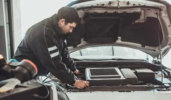 One young auto mechanic doing service of car's air conditioning system in repair shop.