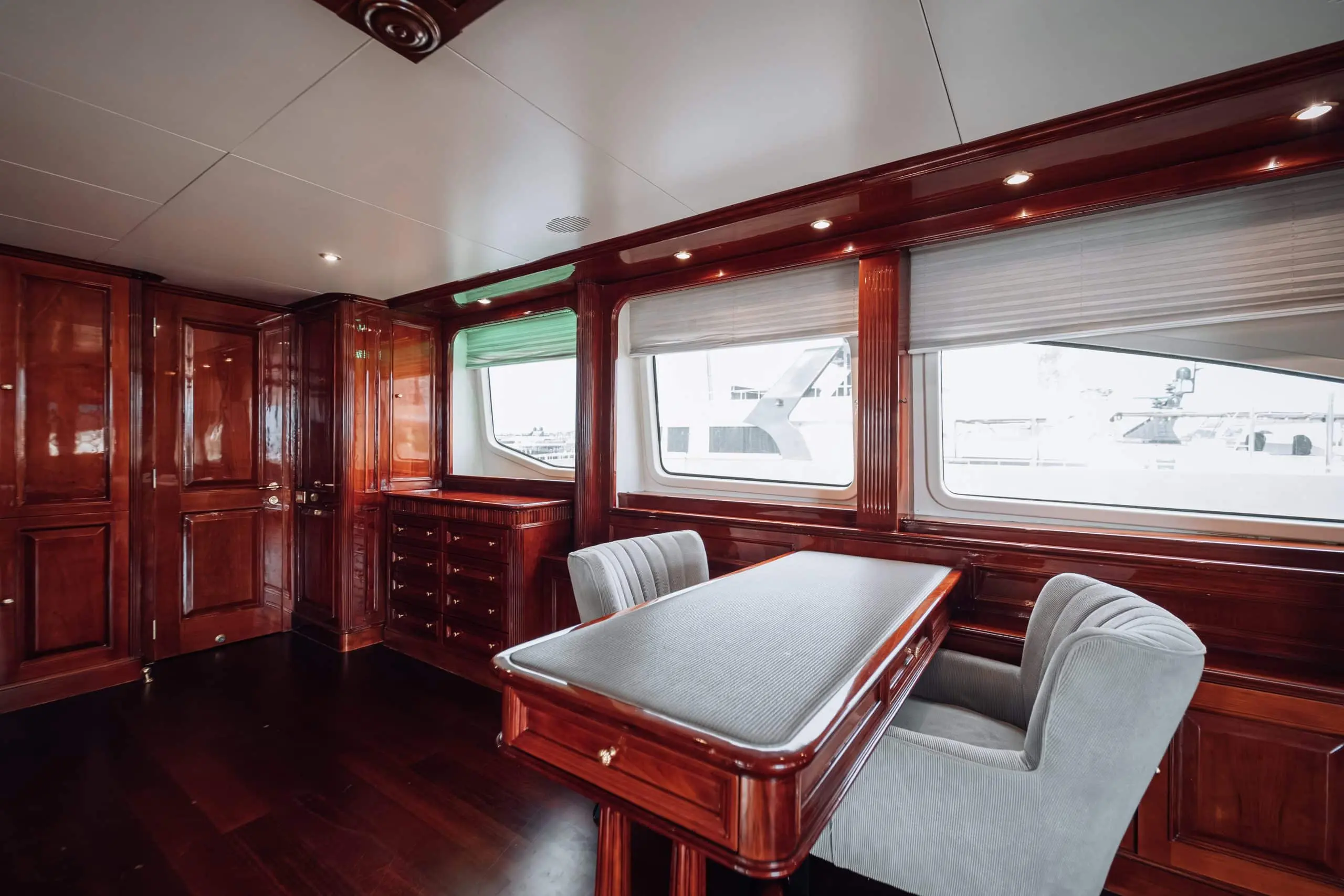 Luxury yacht dining area with polished wooden interiors and panoramic windows.