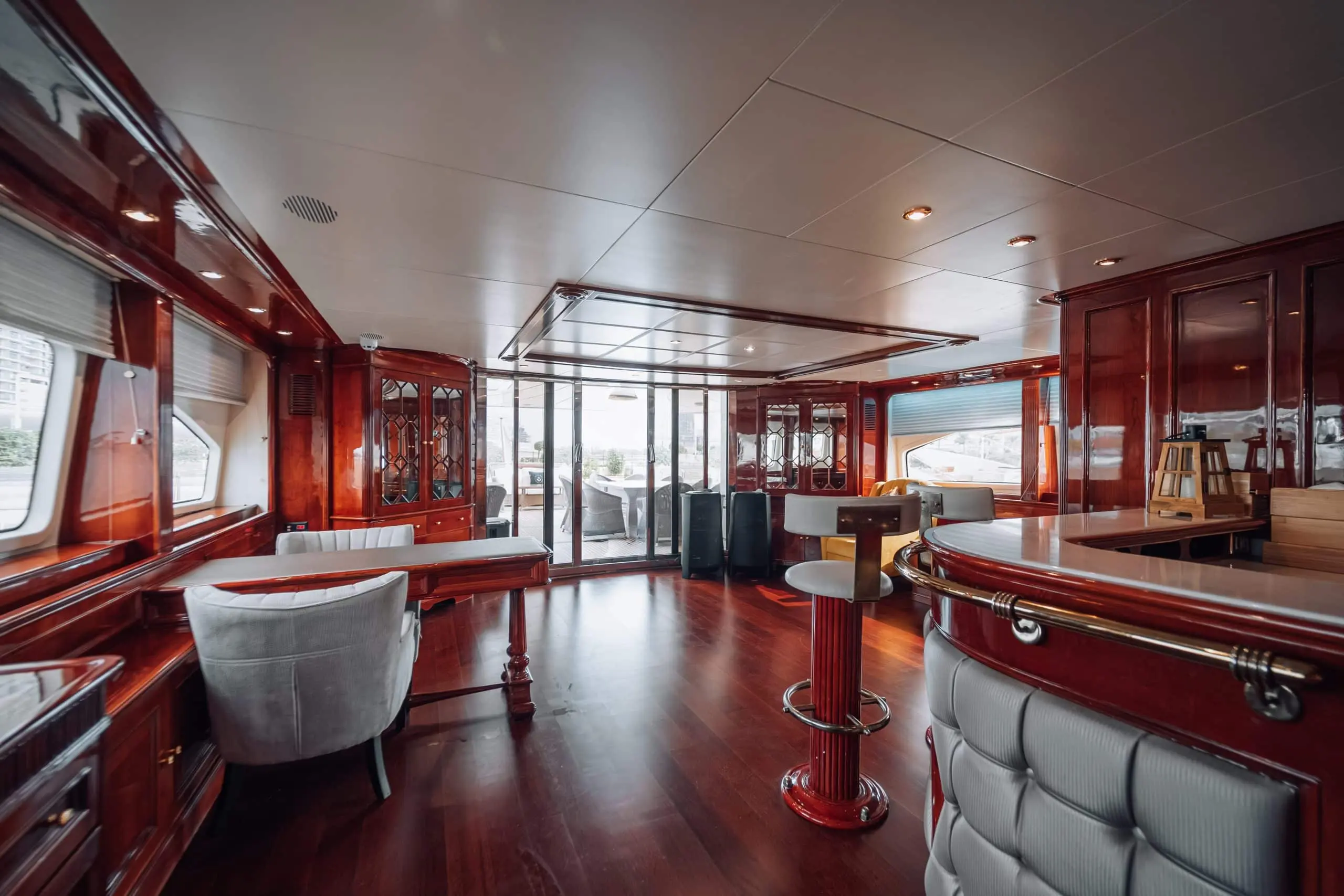 Luxury yacht lounge interior with polished wooden finishes and panoramic deck access.