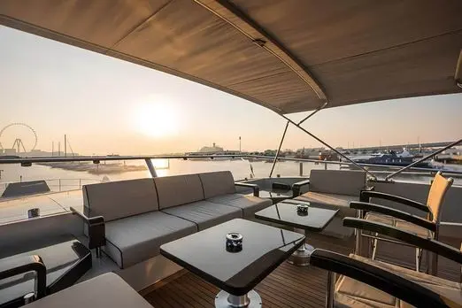 Baglietto 110 yacht upper deck lounge with cushioned seating, wooden ceiling and sunset sea views
