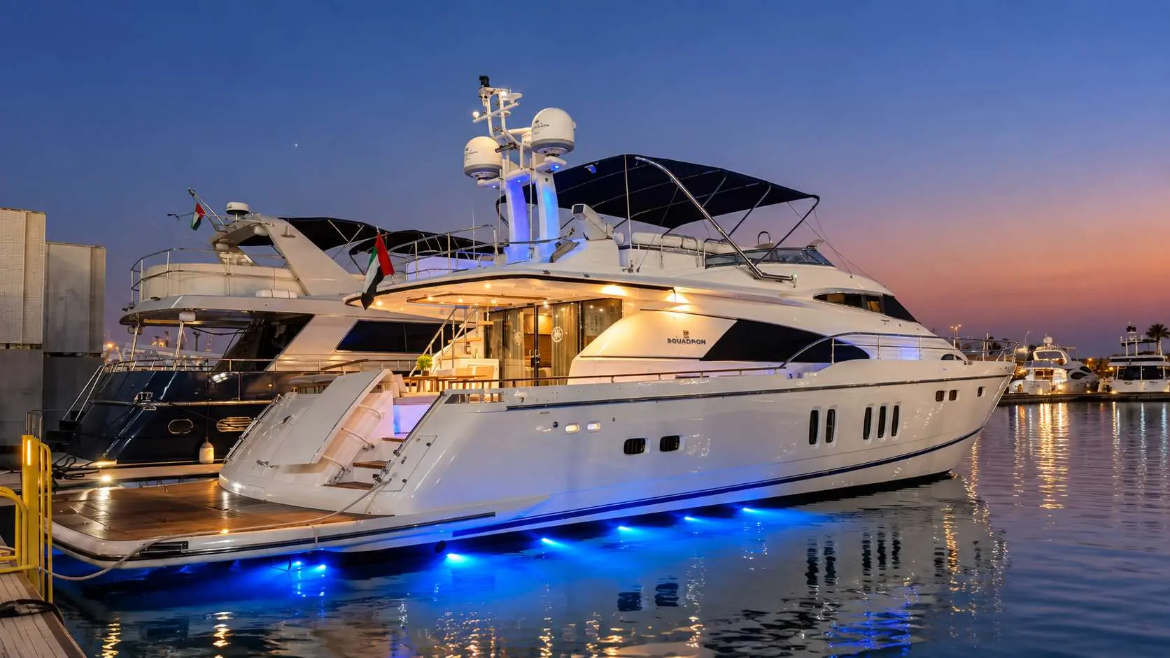 Empress 80 yacht at dusk with underwater lights, Dubai Harbour
