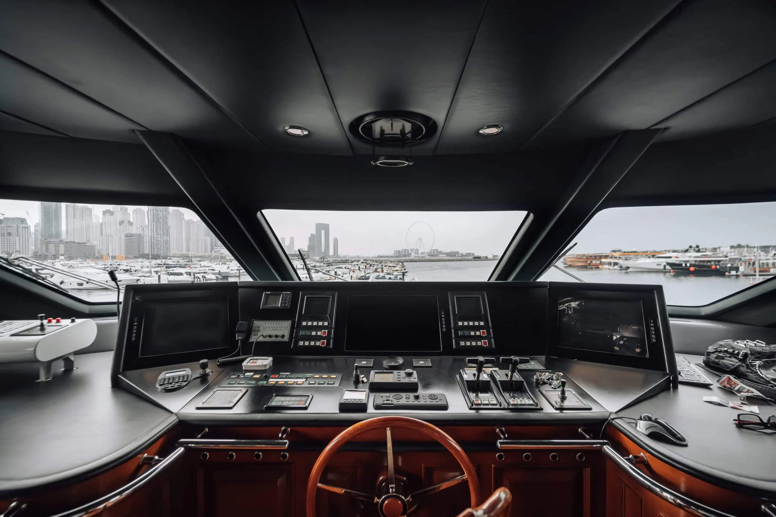 Luxury yacht helm station with advanced navigation controls and panoramic marina view.