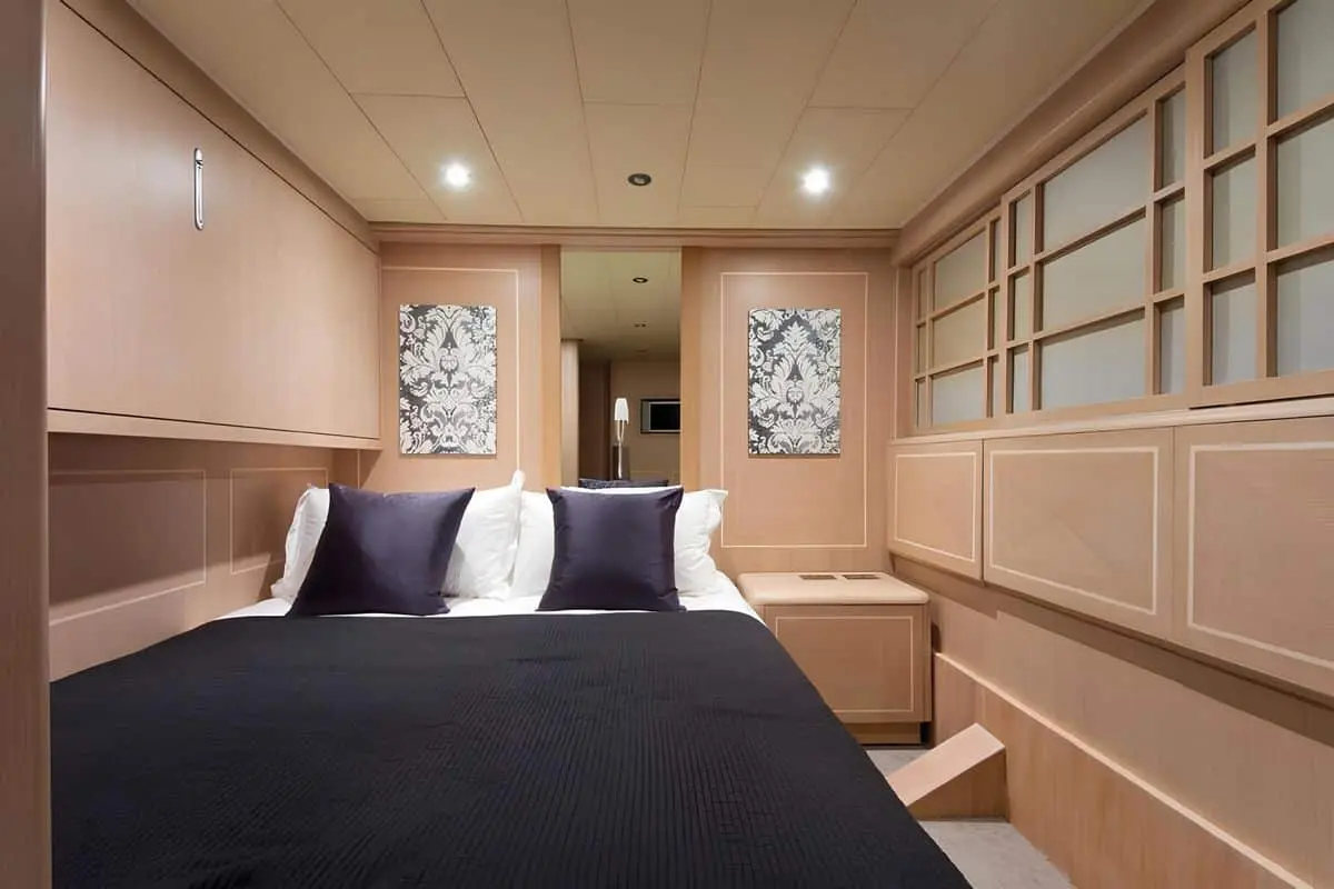 Elegant guest cabin aboard Baglietto 110 yacht with twin beds, soft lighting, and wood-paneled walls