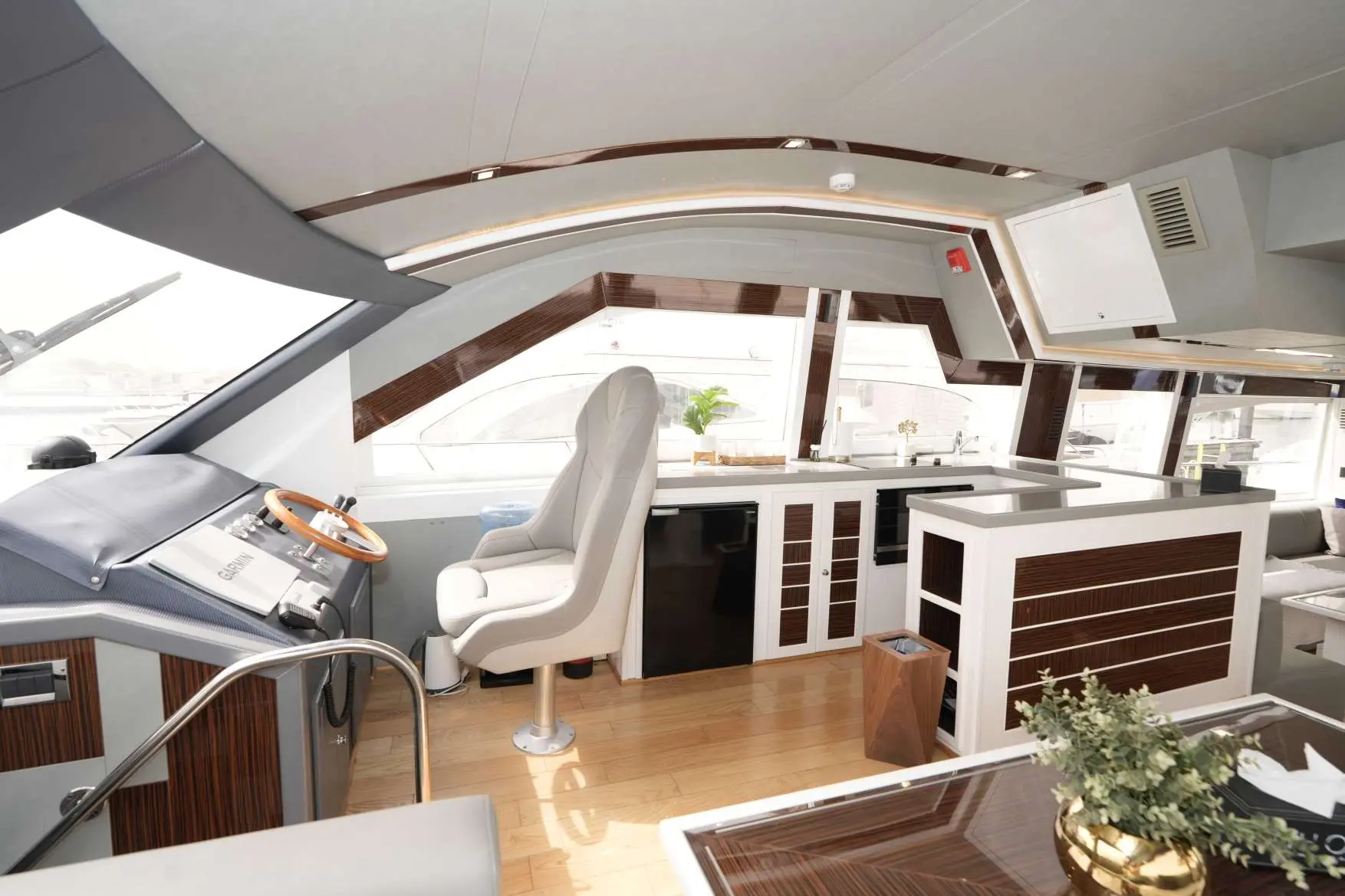 Belle 75 yacht helm station and galley area with modern wood finishes and captain’s chair.