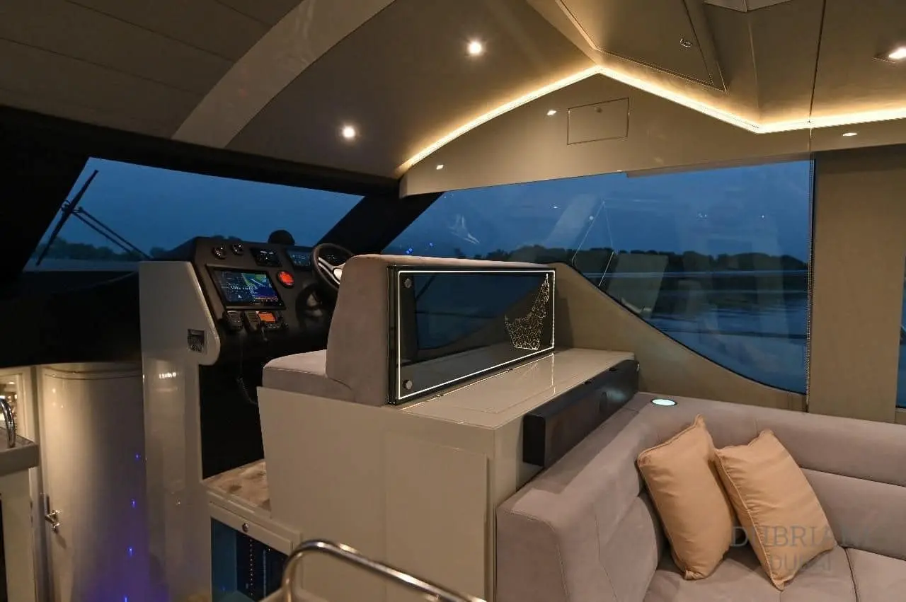 Novia 55 interior helm and adjoining sofa in the evening, lit by amber cove lighting