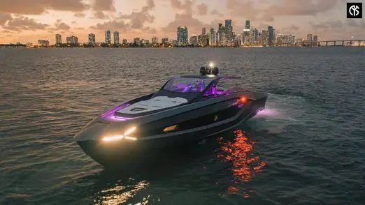 Black Tecnomar for Lamborghini 63 sports yacht lit with purple LEDs on calm water at dusk before a city skyline