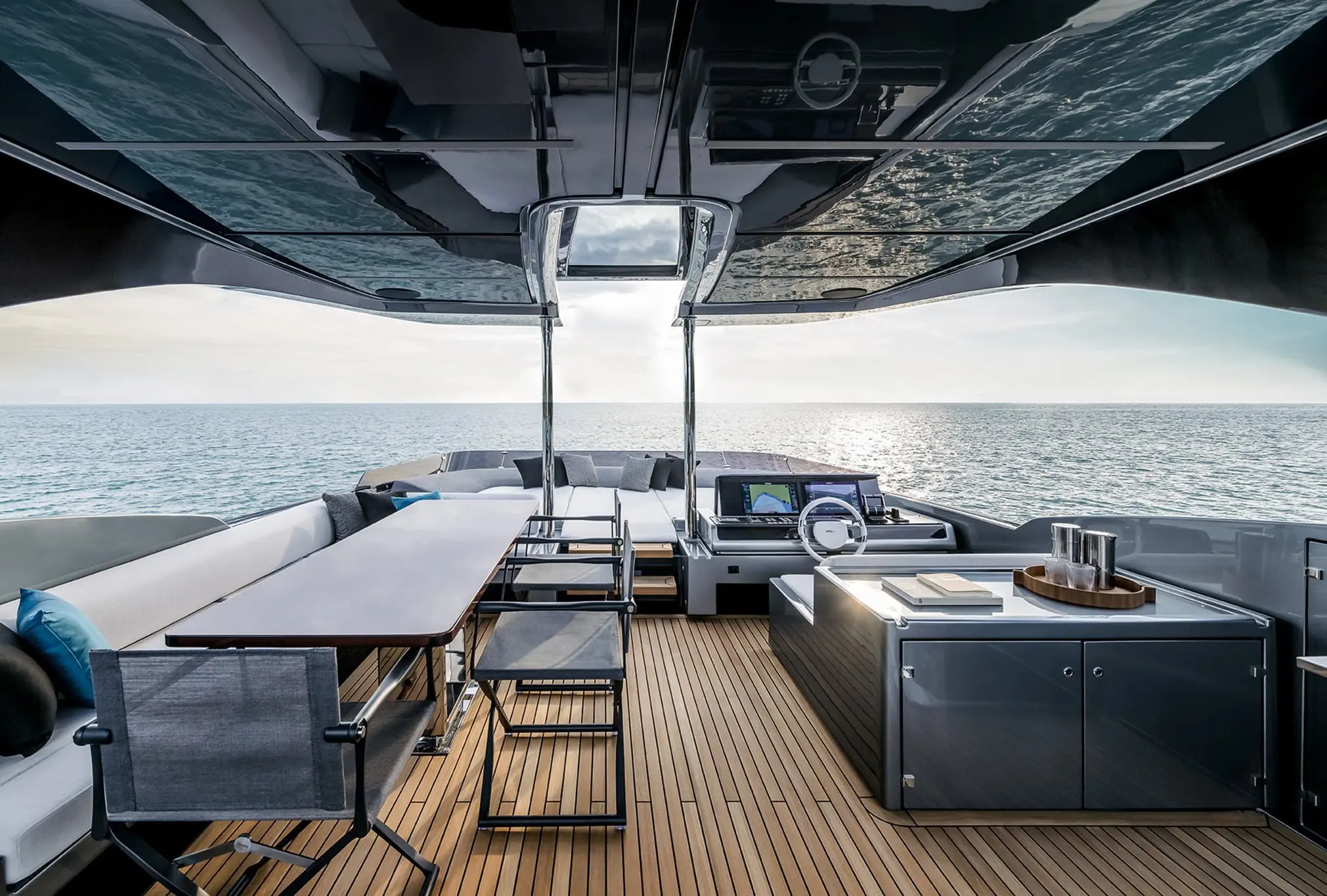 Luxury yacht cockpit with helm station, dining table, and panoramic ocean view
