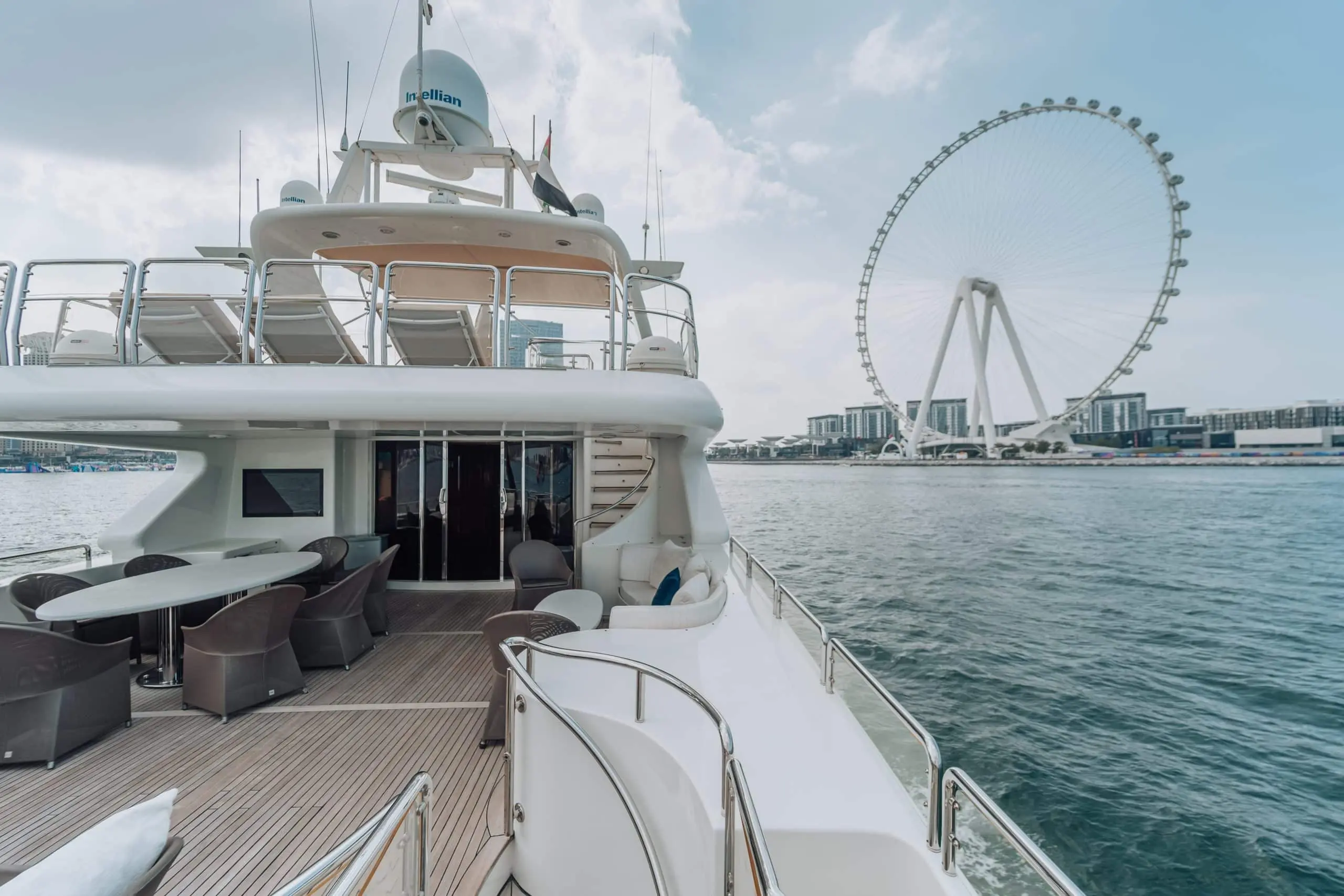 Luxury yacht deck near waterfront Ferris wheel.