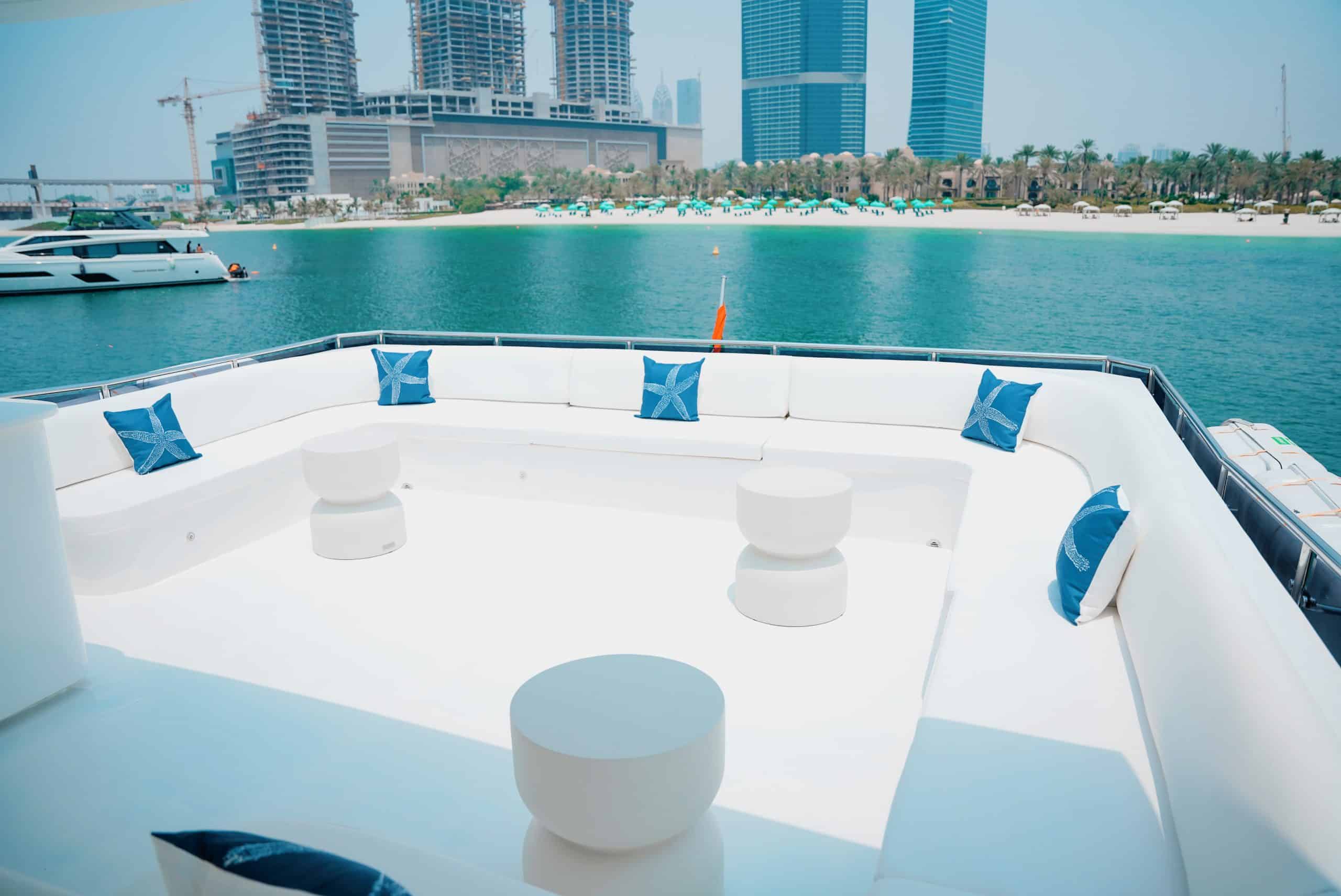 Carina 75 yacht forward lounge seating area with cushions and Dubai skyline in background