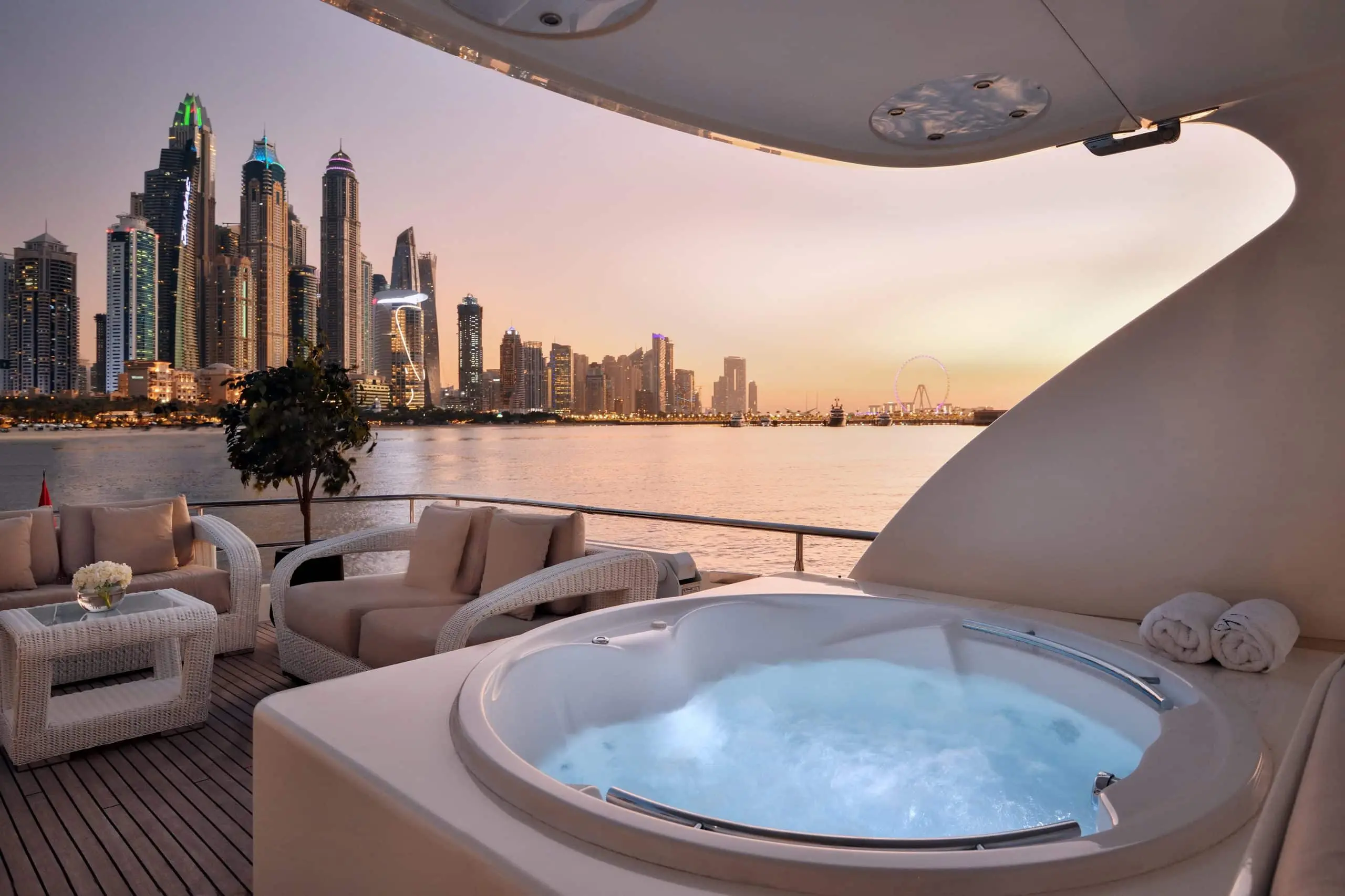 Luxury yacht jacuzzi on deck with Dubai Marina skyline view at sunset