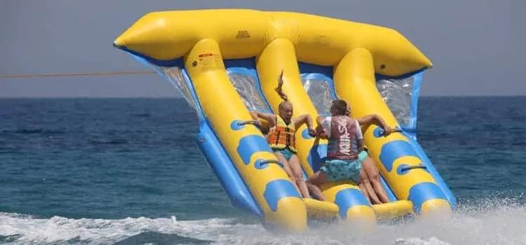 Group enjoying fly fish inflatable water ride with Dubai skyline in background
