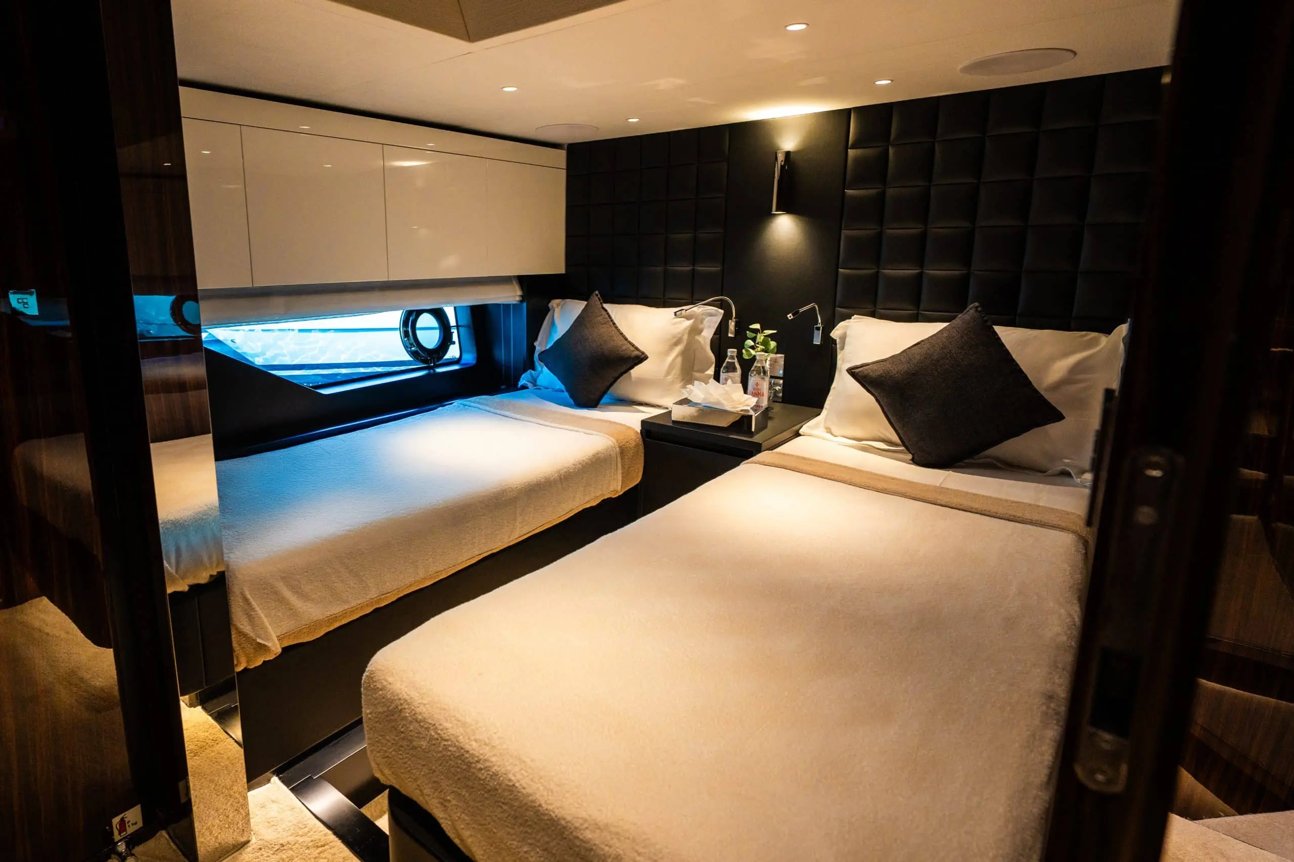Luxury yacht twin guest cabin with padded wall panels and porthole window