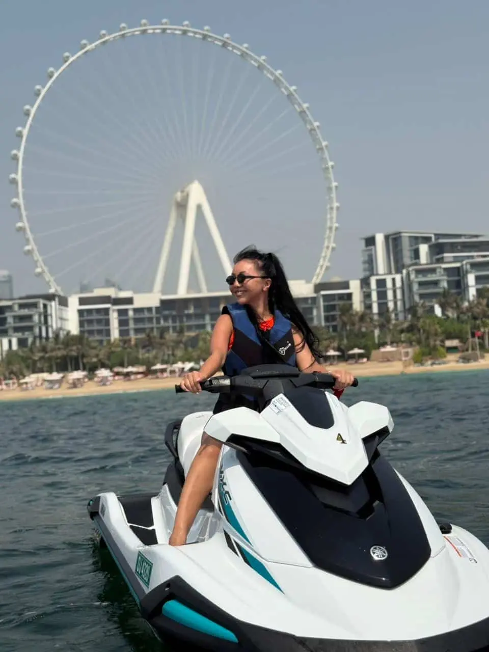 Woman riding white jet ski in Dubai with beachfront skyline background