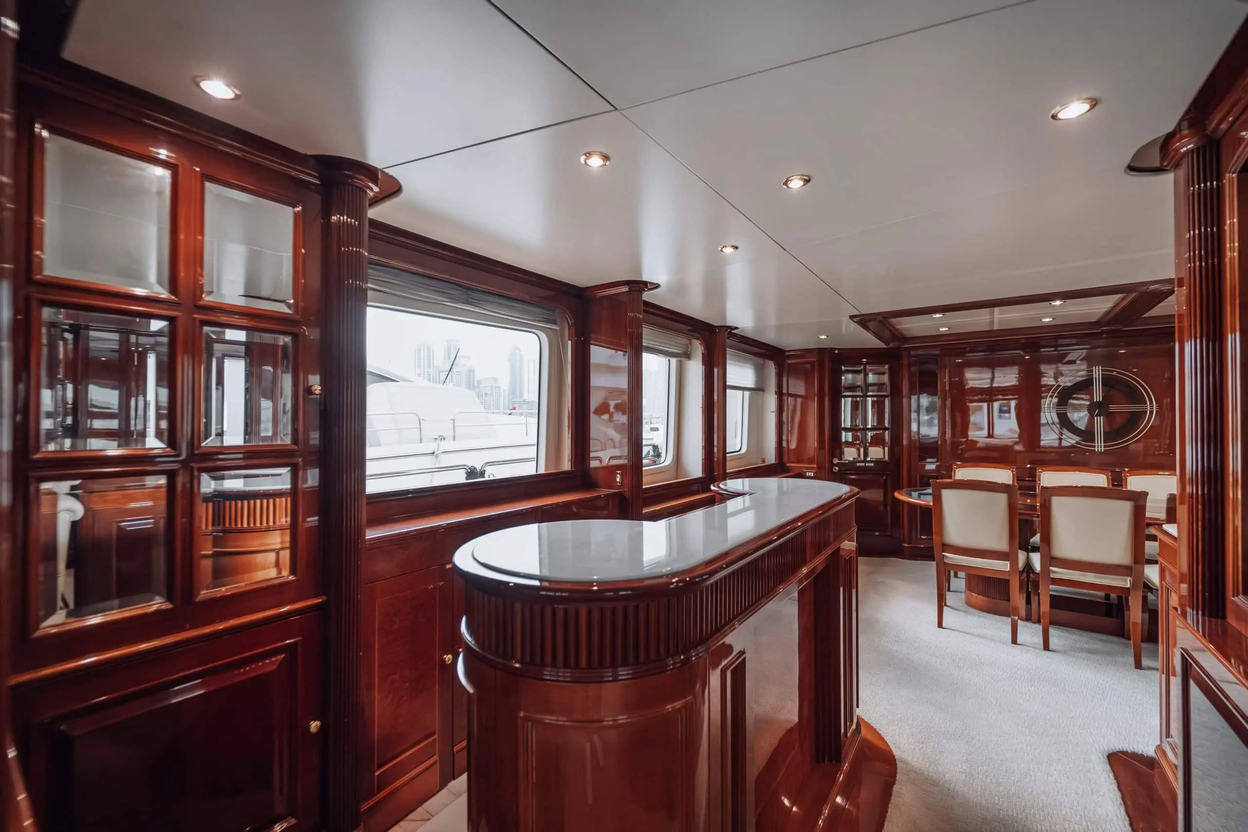 Luxury yacht interior with polished wooden bar counter and elegant dining area.
