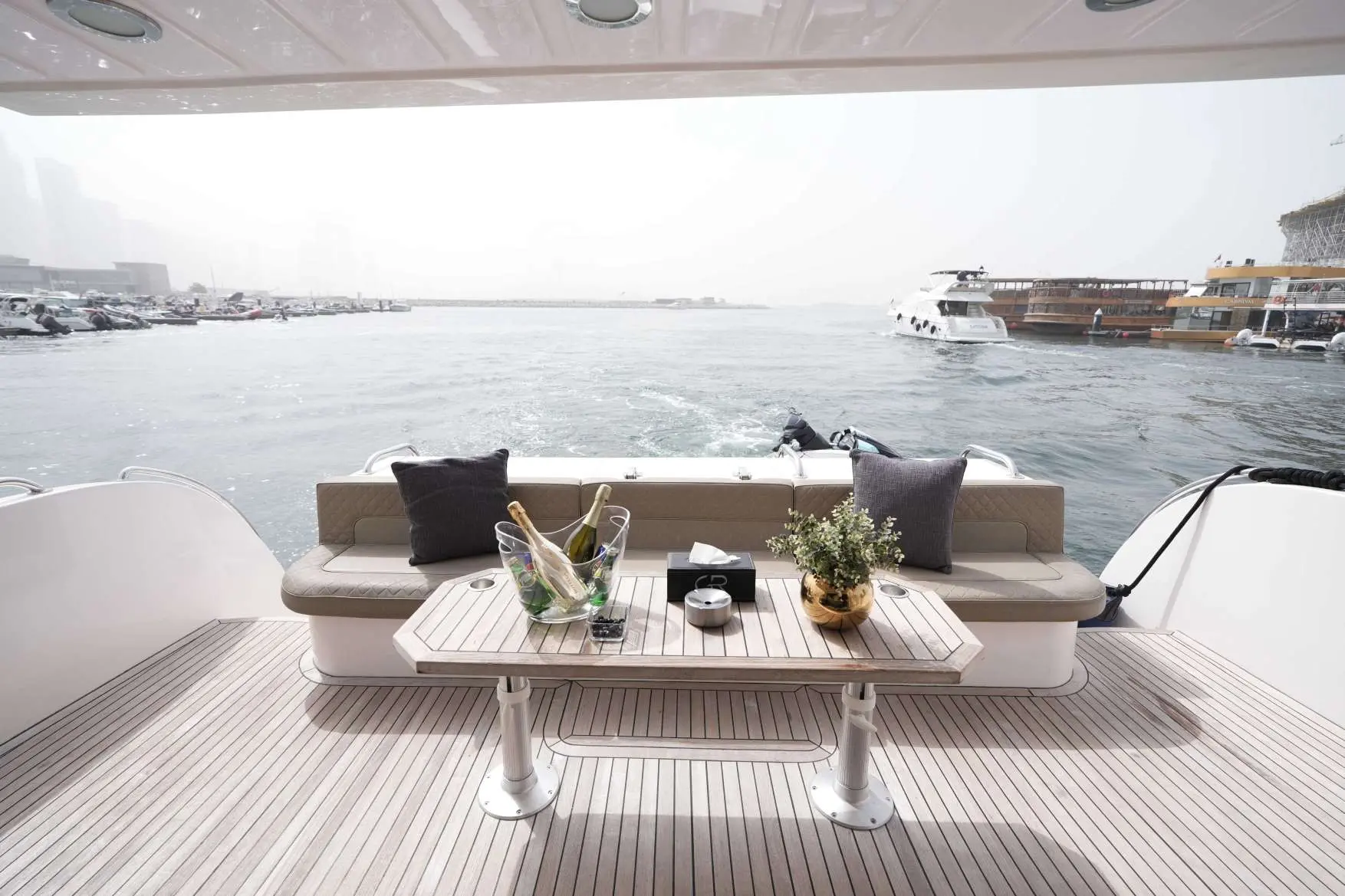 Belle 75 luxury yacht rear deck seating area with table and marina water view