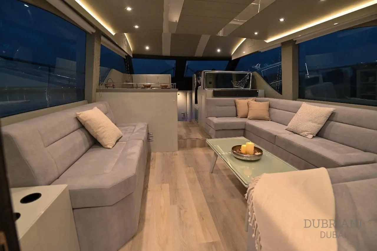 Novia 55 salon at night with grey sofas, glass coffee table and warm LED cove lighting