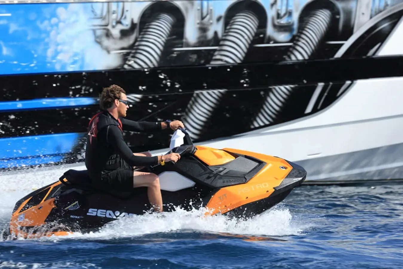 Baia 100 at anchor with jet ski running alongside the hull