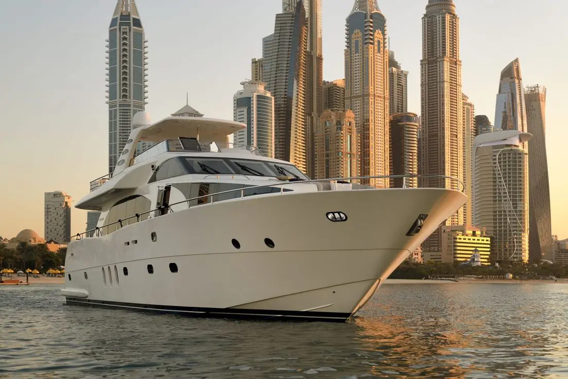 Luxury yacht exterior cruising near Dubai skyscrapers at sunset