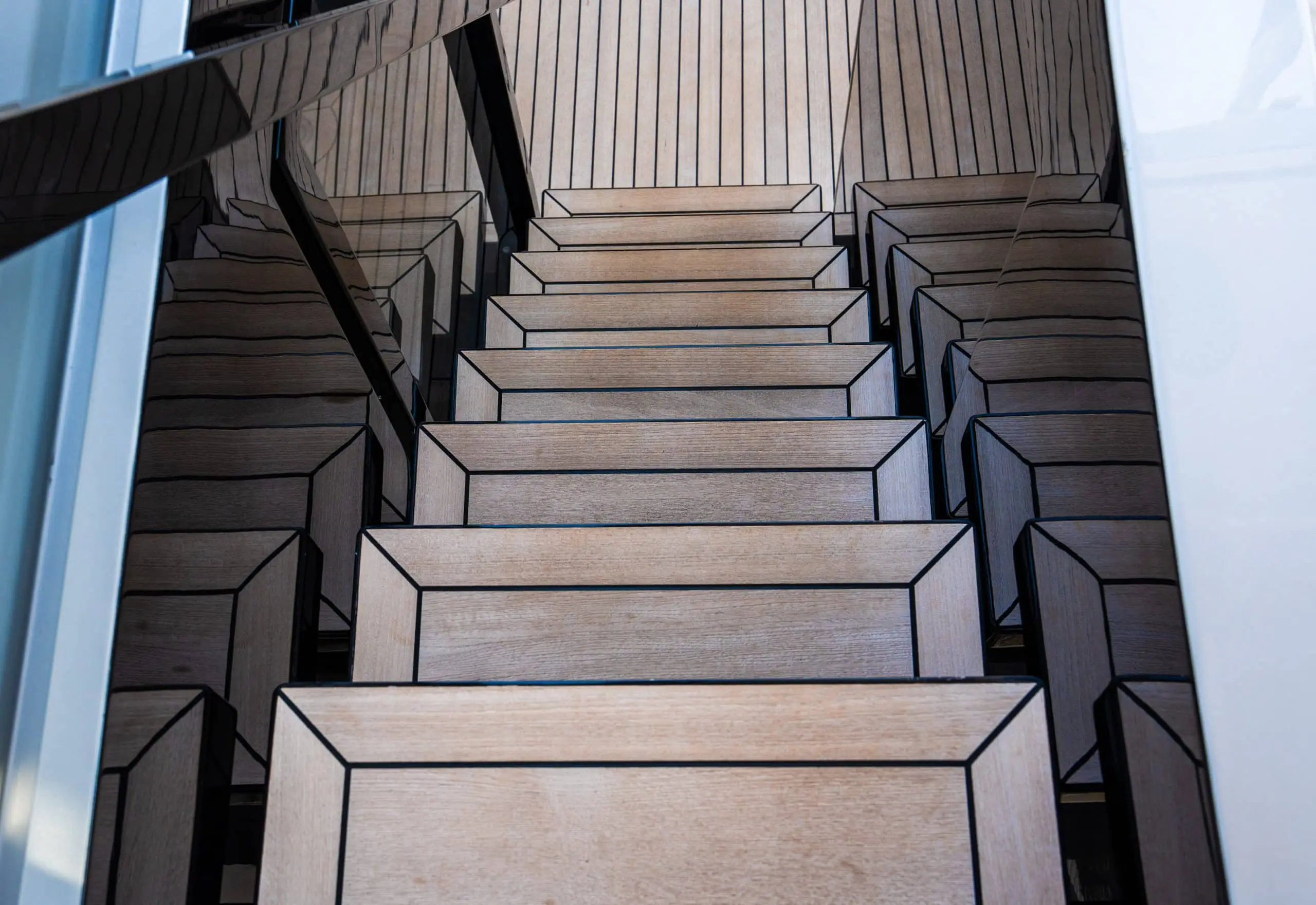 Teak wood staircase with modern metal railings on a luxury yacht