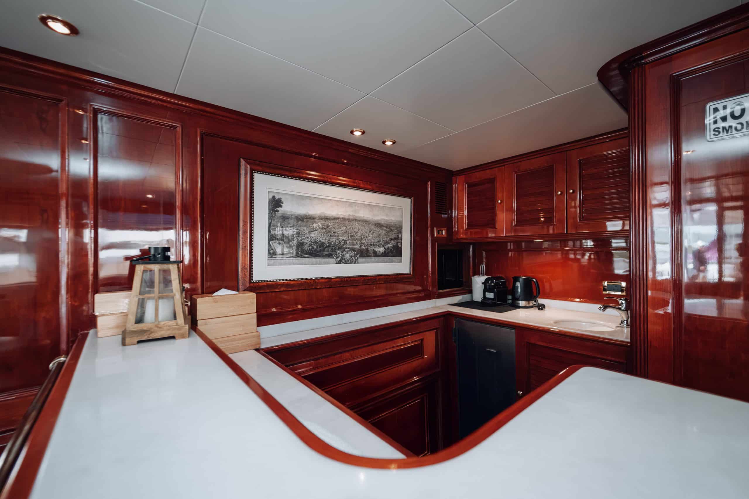 Luxury yacht interior galley with polished wooden cabinets and modern amenities.