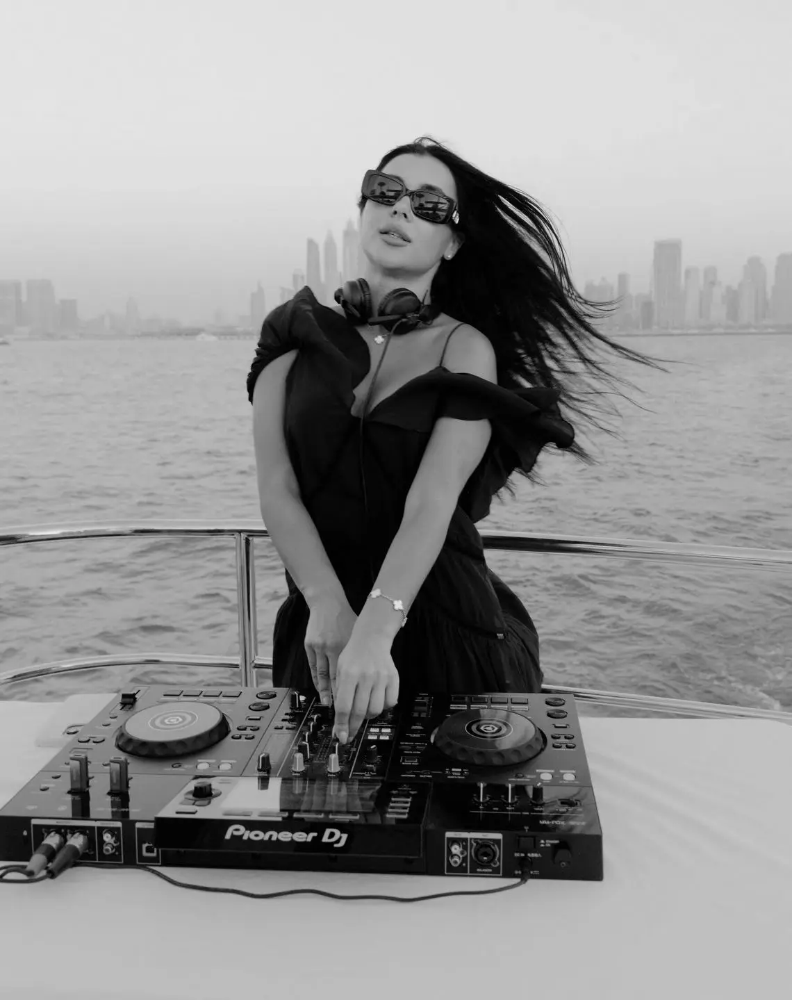 Professional female DJ mixing music onboard yacht with ocean backdrop