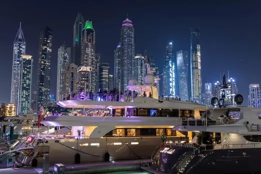 MILA 141 luxury yacht illuminated at night with Abu Dhabi skyline backdrop