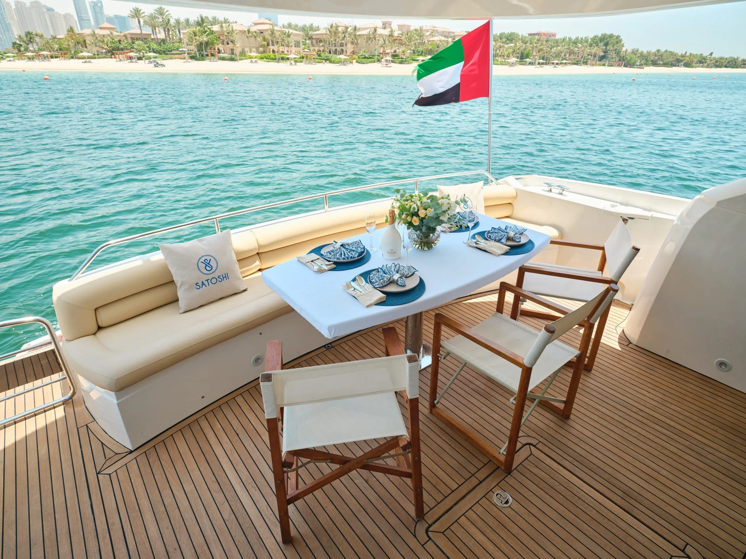 Sunseeker Satoshi 70 aft deck dining setup with UAE flag in Abu Dhabi