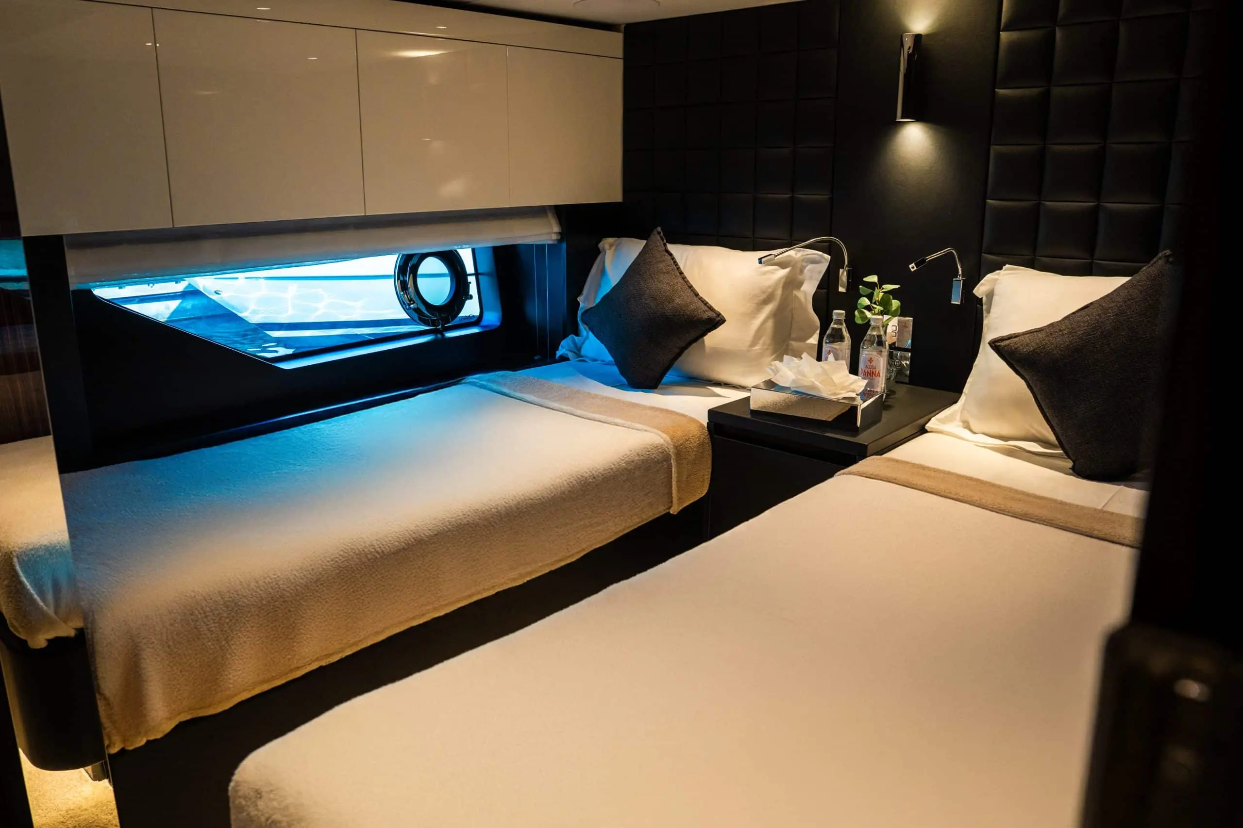 Twin-bed guest cabin with porthole window on a luxury yacht