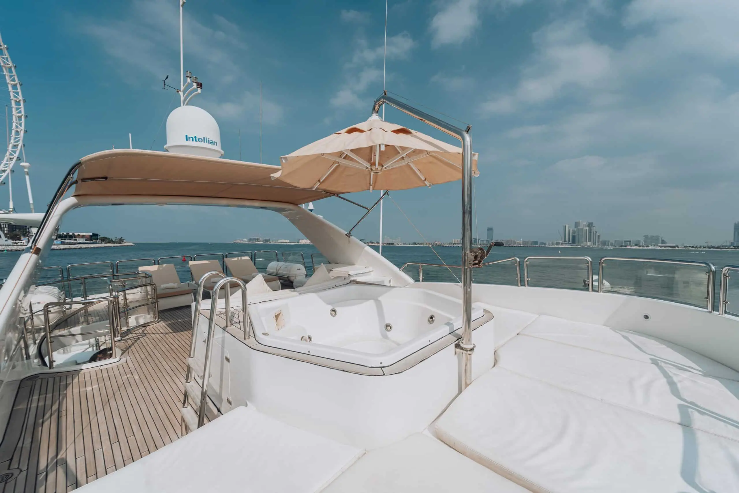 Luxury yacht deck with jacuzzi and Dubai skyline view.