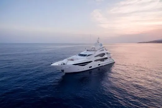 White superyacht cruising alone across calm open water under a soft pink dusk sky