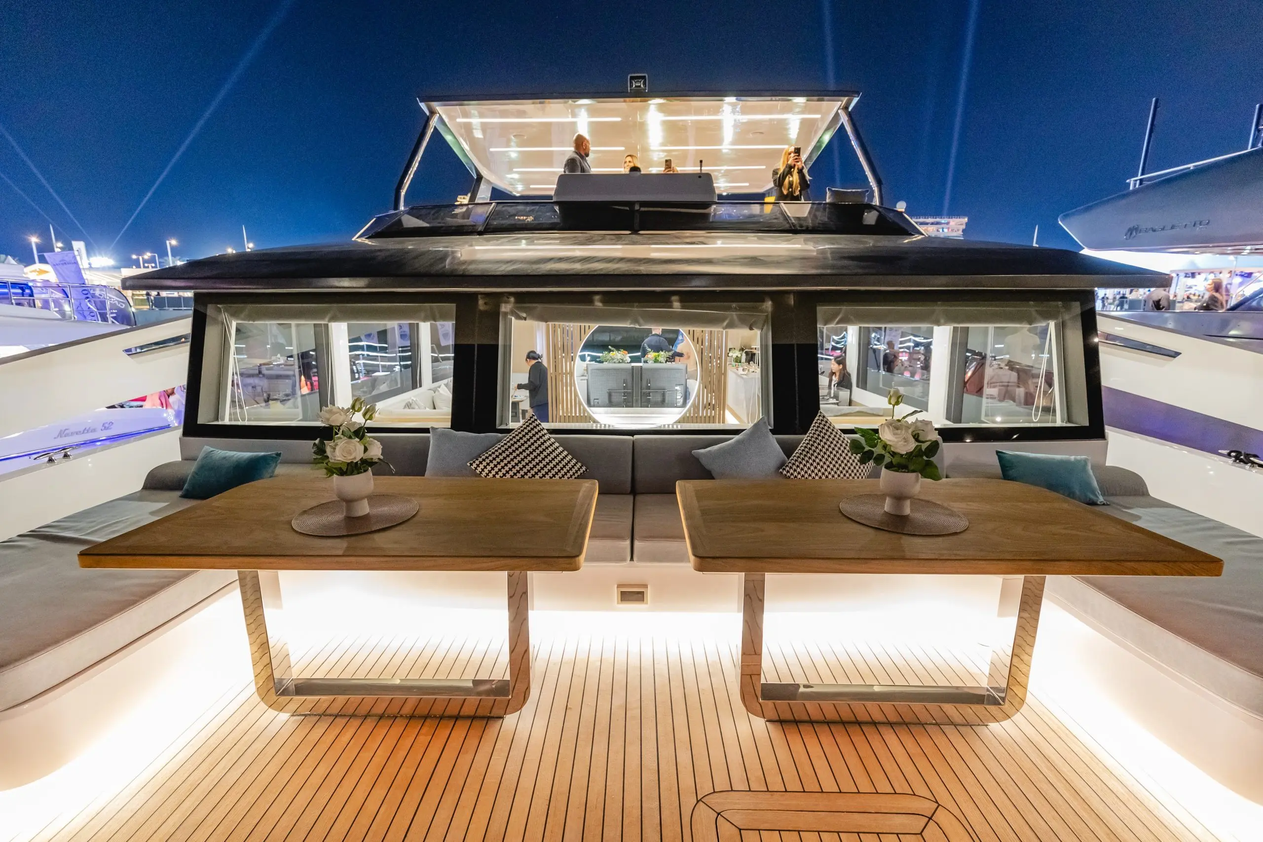 Zirve 72 luxury yacht upper deck at night with illuminated seating and wooden flooring