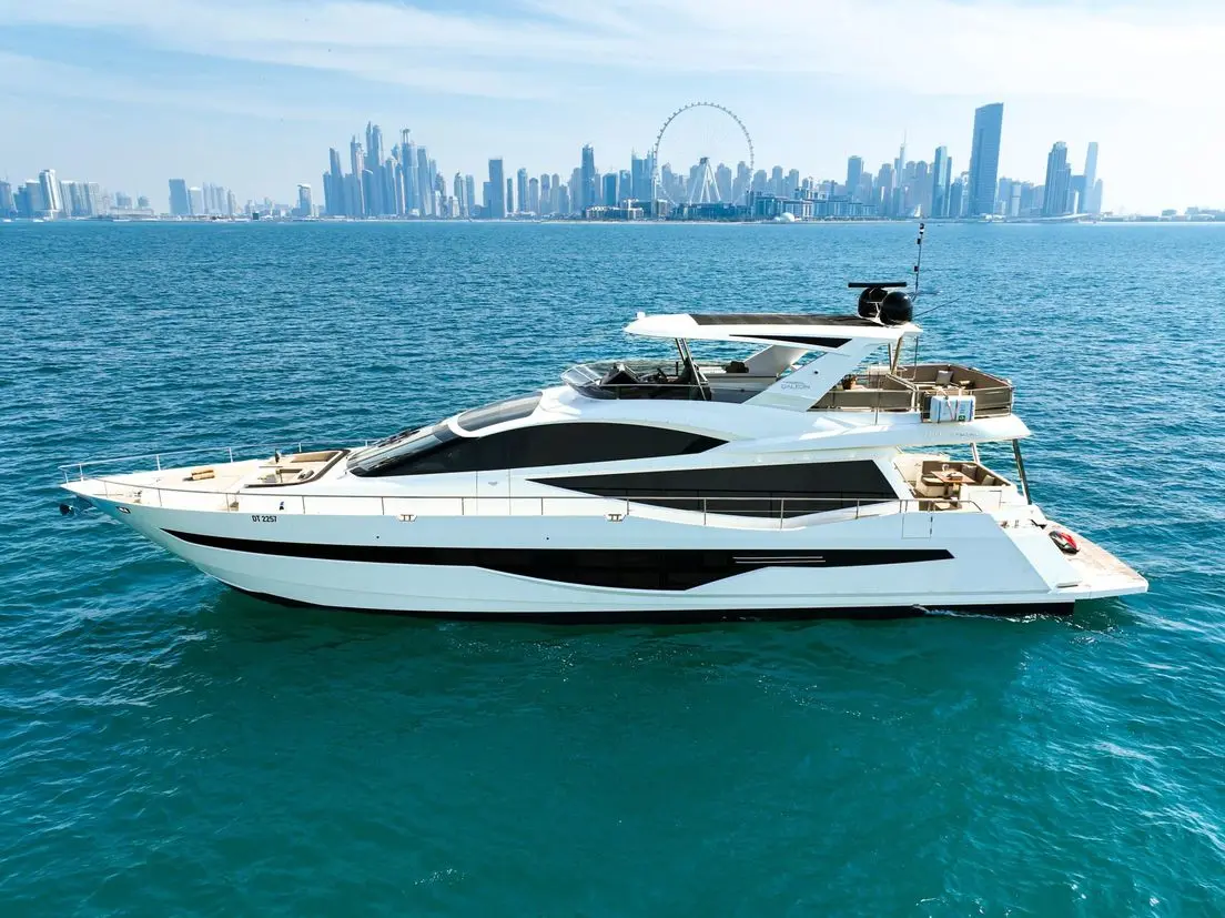 Galeon 780 F1 luxury yacht side view cruising on clear blue sea with modern skyline background