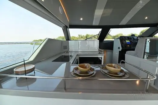 Novia 55 galley counter with plates and bowls, the interior helm dash visible beyond