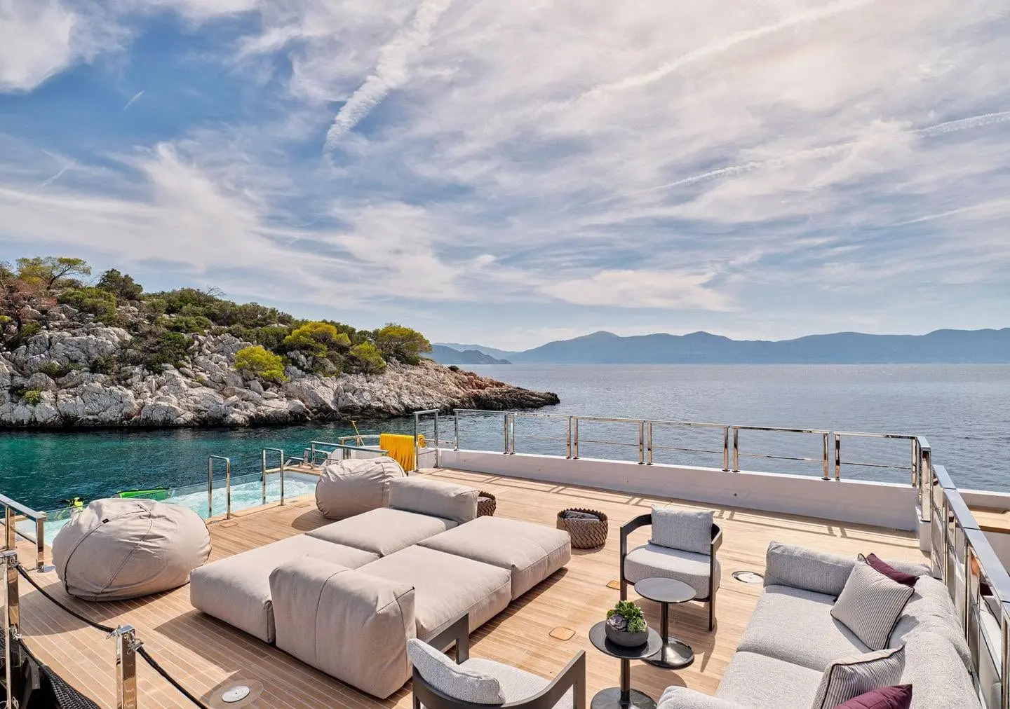 Sanlorenzo 500EXP aft deck lounge with coastal view, broker photo