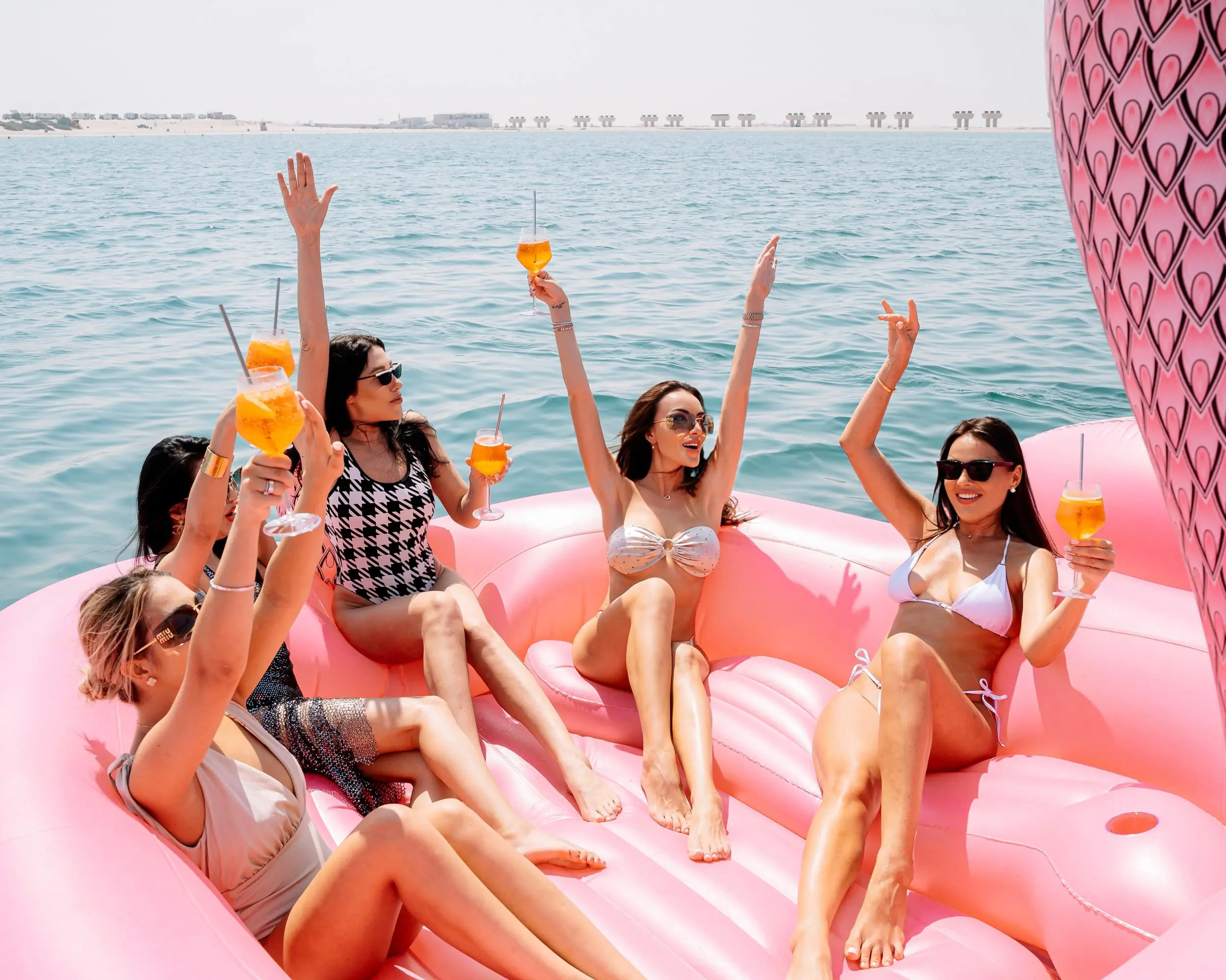 Women celebrating birthday on yacht with pink pool floats in Dubai
