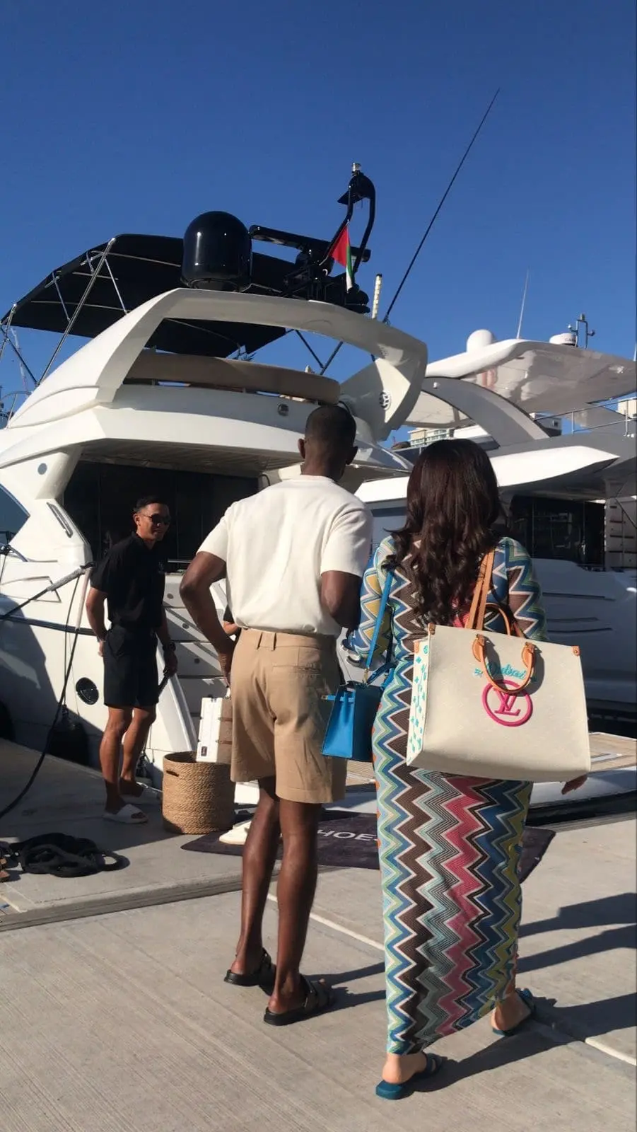 Guests met by crew on the dock as they prepare to board a white flybridge motor yacht in Dubai