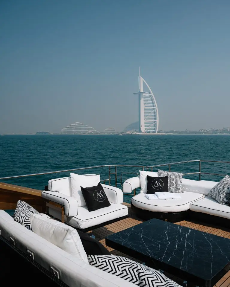 Yacht foredeck lounge with white sofas and patterned cushions facing the Burj Al Arab across the water