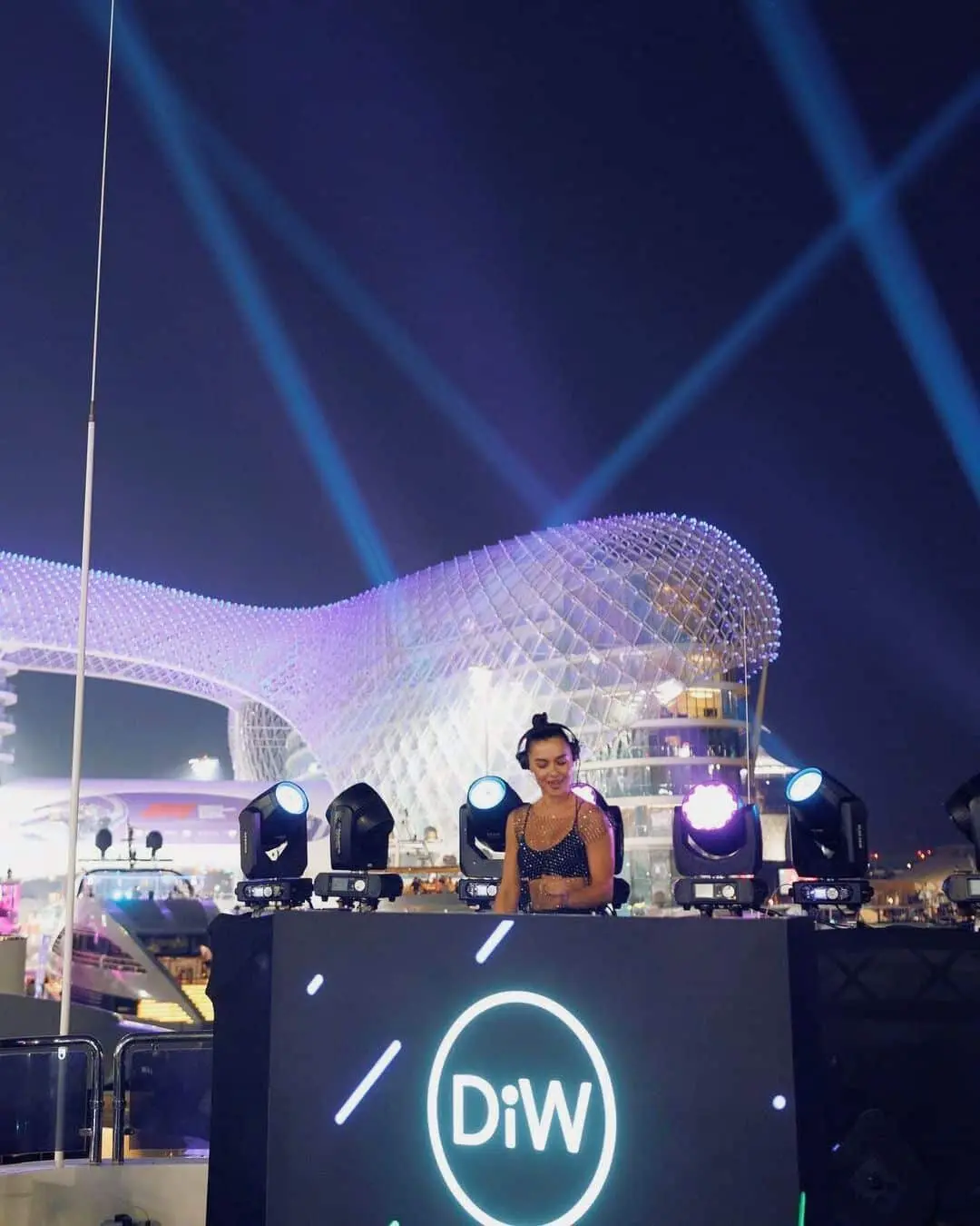 Live DJ performing at luxury outdoor waterfront event with stage lighting